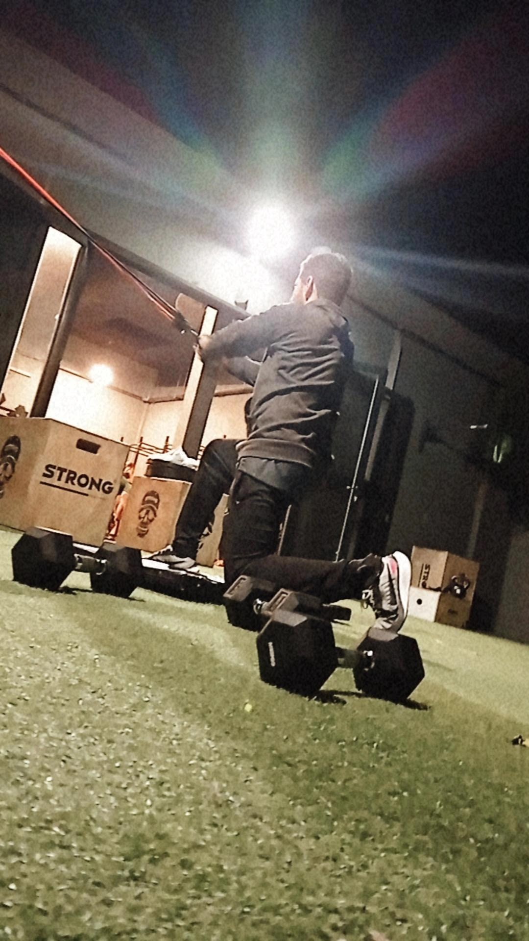 Gym trainer coach correcting posture and form of a trainee during deadlift exercise with olympic barbell in Muñiz